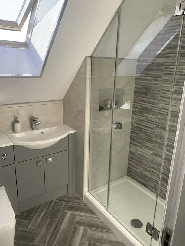 A modern bathroom with an built in shower with a slanted glass screen 