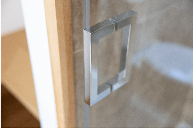 A close up of a silver shower door handle