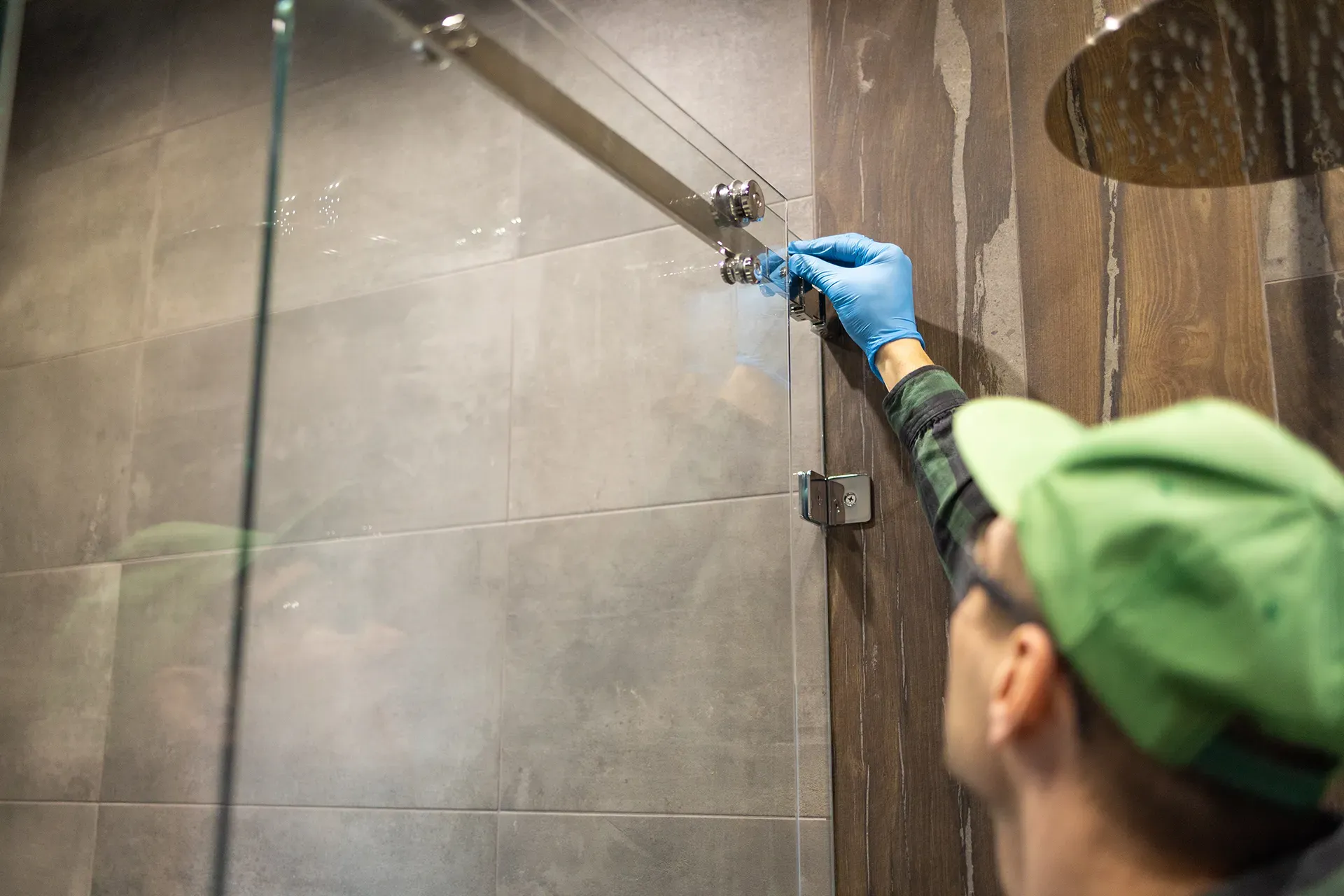 A worker installing a glass door onto a shower 